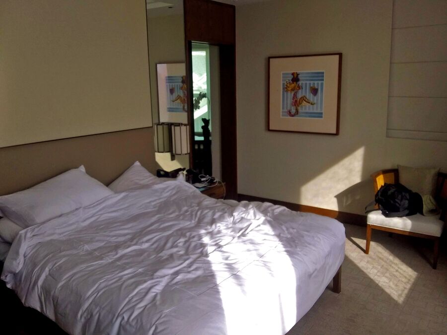 Dormitorio con la cama hecha y varias almohadas apiladas