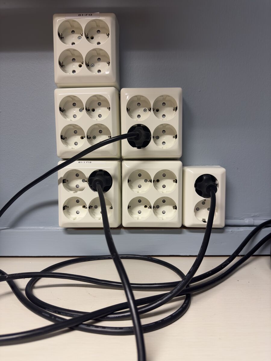 Pared con numerosas bases de enchufe y varios cables conectados