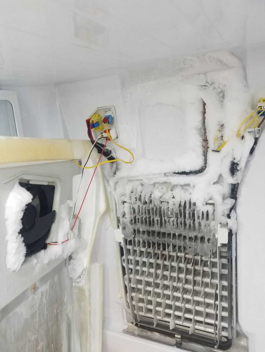 Evaporador de un frigorífico cubierto de hielo con el panel interior desmontado