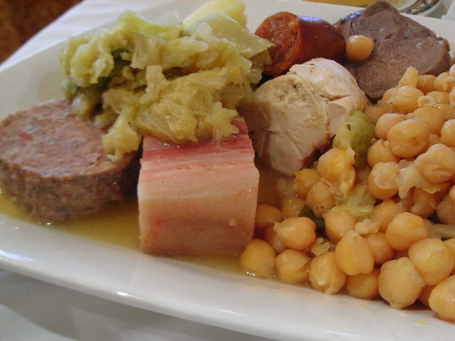 Plato de cocido con garbanzos enteros, repollo, chorizo, tocino y carne