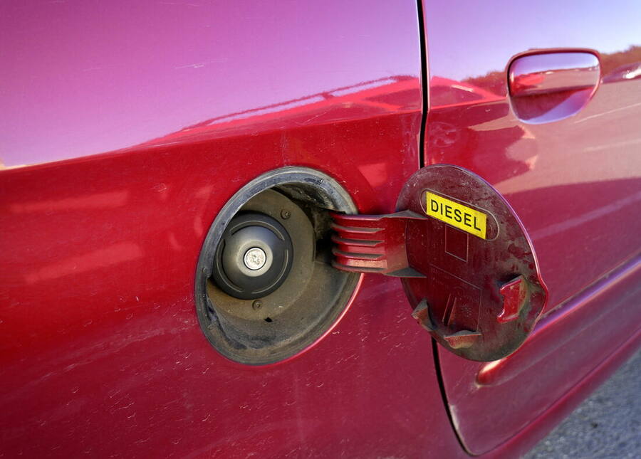 Boca de llenado de un coche con el tapón quitado y la trampilla abierta, con la etiqueta de diésel a la vista