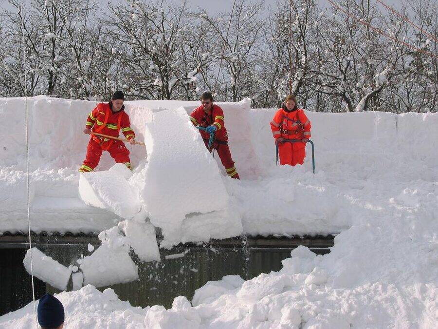 Operarios cortando y retirando grandes bloques de nieve compactada de una cubierta plana
