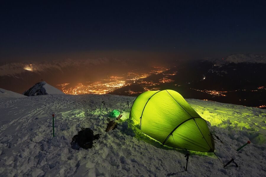 Tienda de campaña verde montada sobre un terreno de montaña nevado
